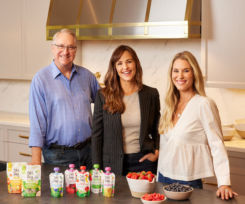 Our founders standing in a kitchen with various pouches and bowls of fruit on the counter.
